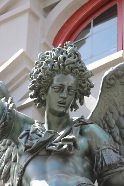 Bronzestatue eines geflügelten Engels mit wehenden lockigen Haaren.