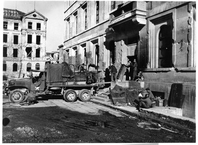 Schwarzweißfoto. Ein LKW parkt vor einem Hauseingang und verlädt Kunstwerke.