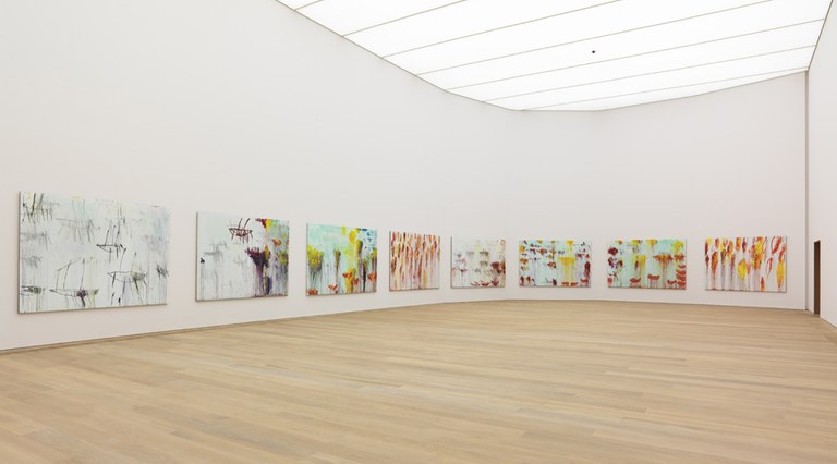 Foto einer Ausstellungsansicht mit bunten Kunstwerken an den weißen Wänden.