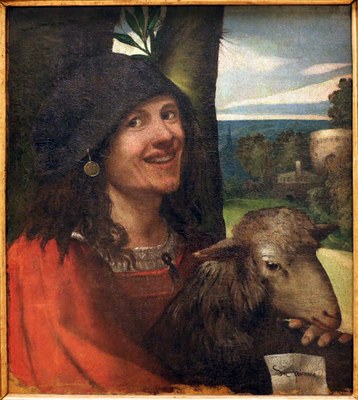Lachender junger Mann mit Schaf auf dem Schoß. Porträt