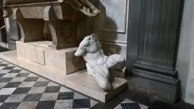 Marmorner Männertorso auf Steinpodest auf schwarz-weißem Schachbrettboden.