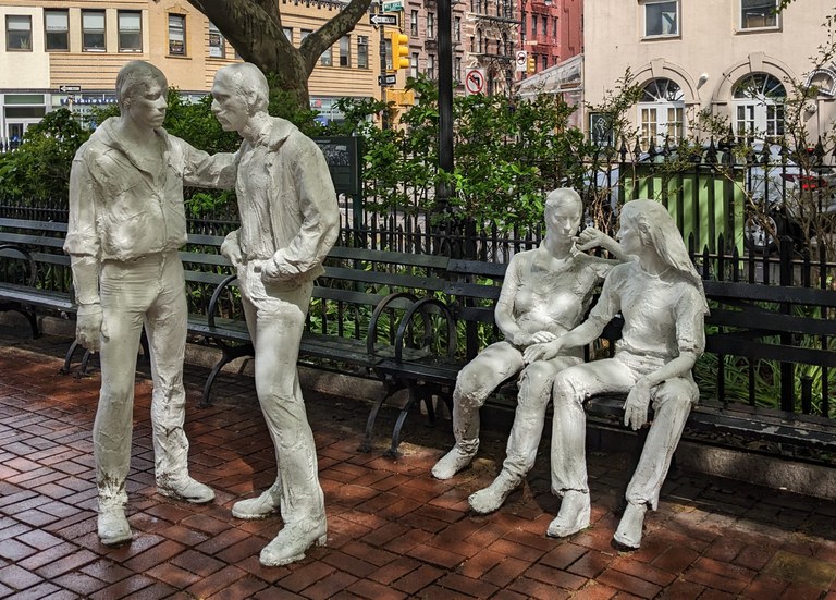 Skulpturengruppe im öffentlichen Raum. Zwei gleichgeschlechtliche Paare. Zwei Männer stehen, zwei Frauen sitzen aus einer Bank.