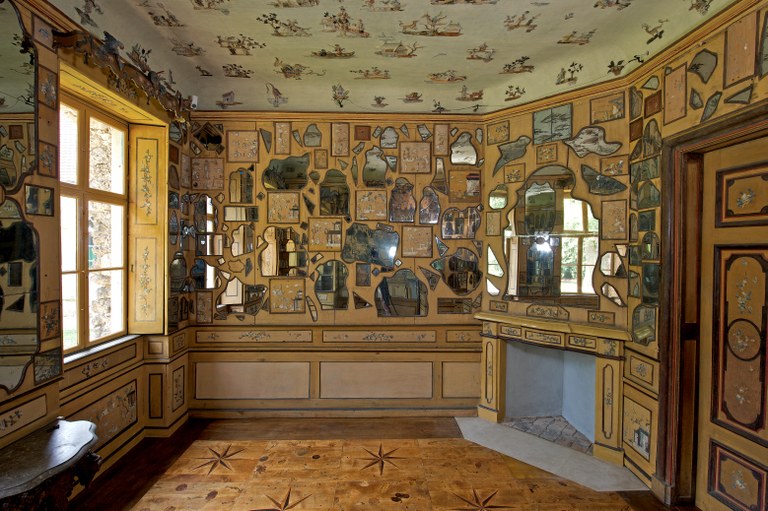 Innenraum mit vielen Spiegeln in verschiedenen Formen. Alle Spiegel hängen an der Wand.